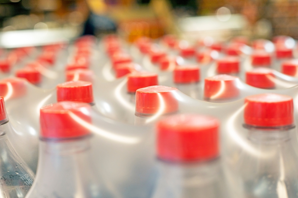 Zbliżenie na folię termokurczliwą do pakowania, w której znajdują się plastikowe butelki - gralapack.com/pl